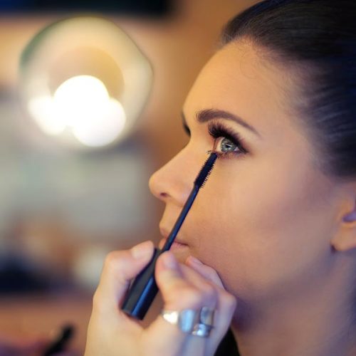 Makeup artist applies mascara. Beautiful woman face. Perfect makeup